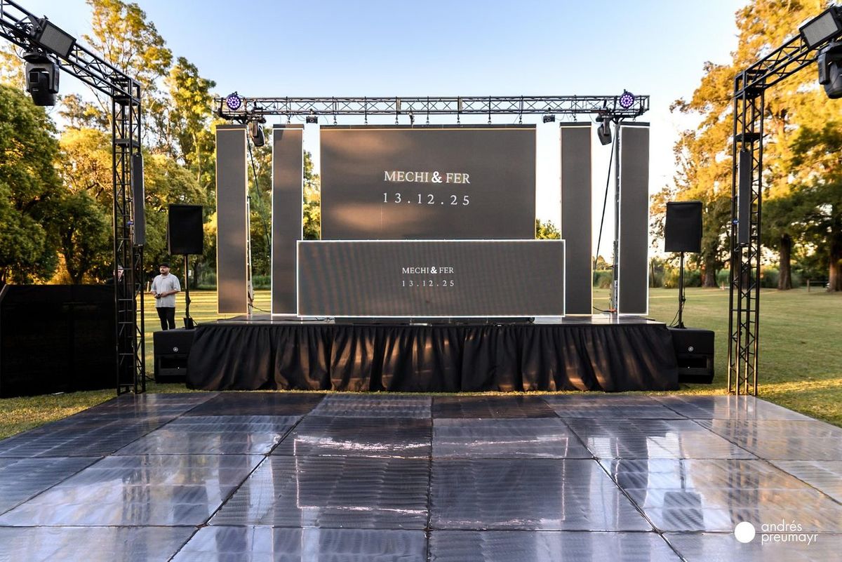 Escenario y pista de acero pulido montados al aire libre, con pantalla LED y estructura de truss para la boda de Mechi y Fer