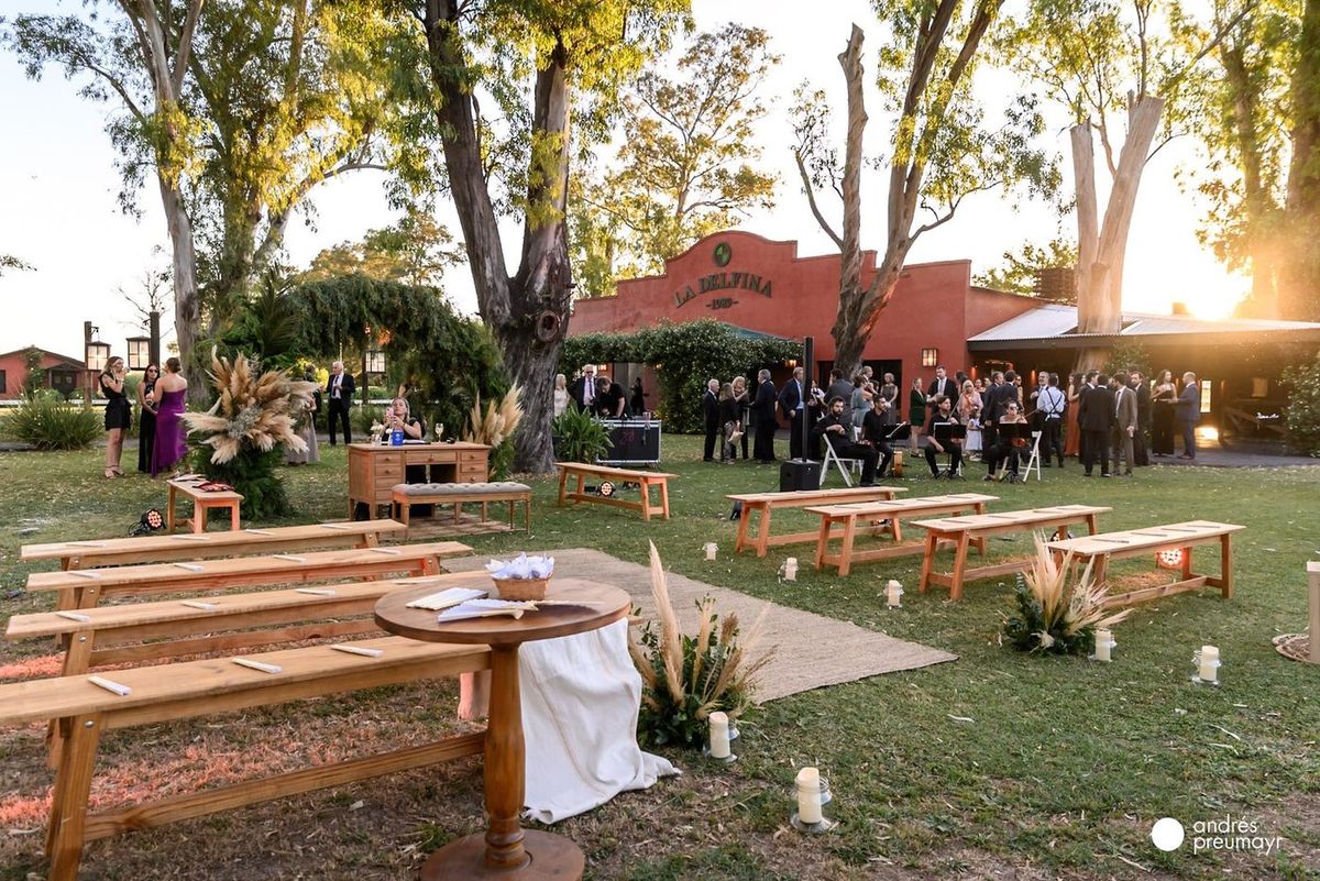 Recepci&oacute;n al aire libre en el parque de La Delfina con bancos de madera y decoraci&oacute;n
