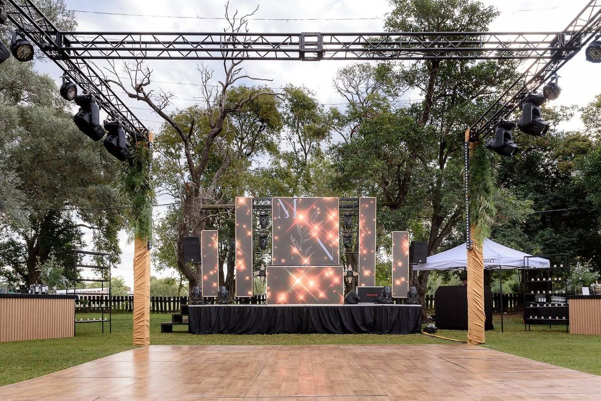 Escenario al aire libre con pantalla LED y pista de deck de madera para la boda de Martina y Nacho en La Delfina